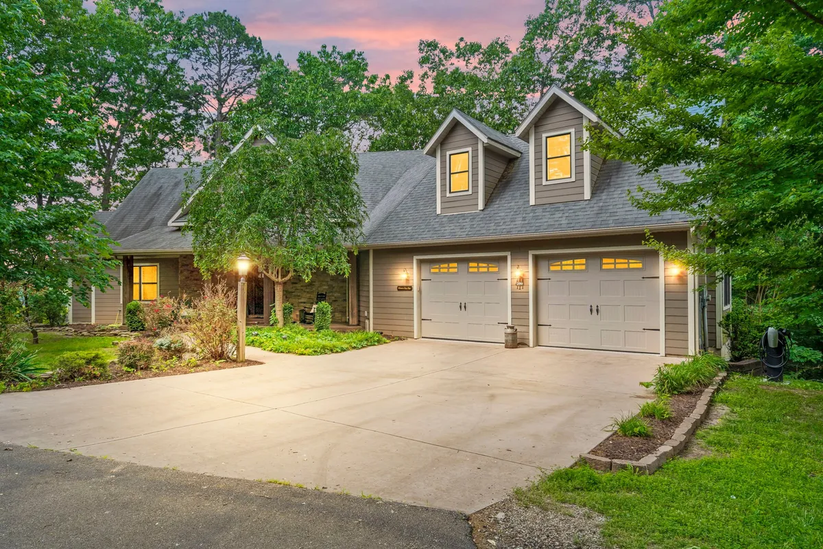 A wide view of the home’s front entrance, garage doors, landscaped garden, stone pathway, and inviting outdoor lighting. The scene is set during the day, with well-maintained vegetation and a welcoming atmosphere.