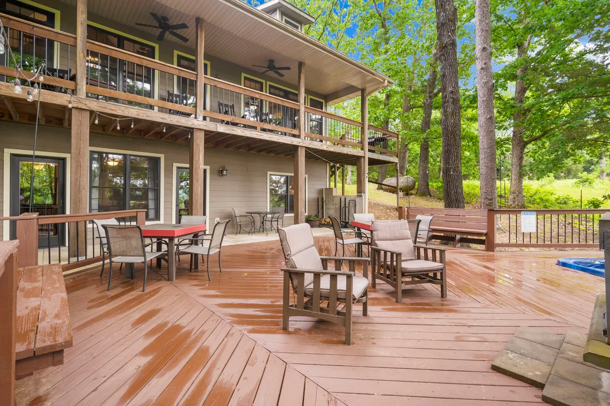A spacious wooden deck furnished with a comfortable seating area and surrounded by lush trees. The elevated position and open atmosphere make it ideal for outdoor dining, morning coffee, or enjoying the sights and sounds of nature from the upper deck vantage point.