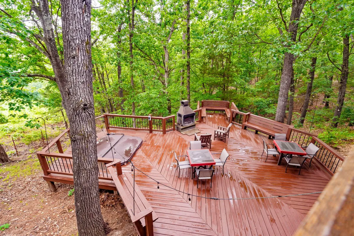An inviting wooden deck area with cozy outdoor seating arranged around a modern fireplace. The deck is enveloped by trees, fostering a communal and tranquil environment perfect for gatherings, stargazing, or winding down after a day of adventure.