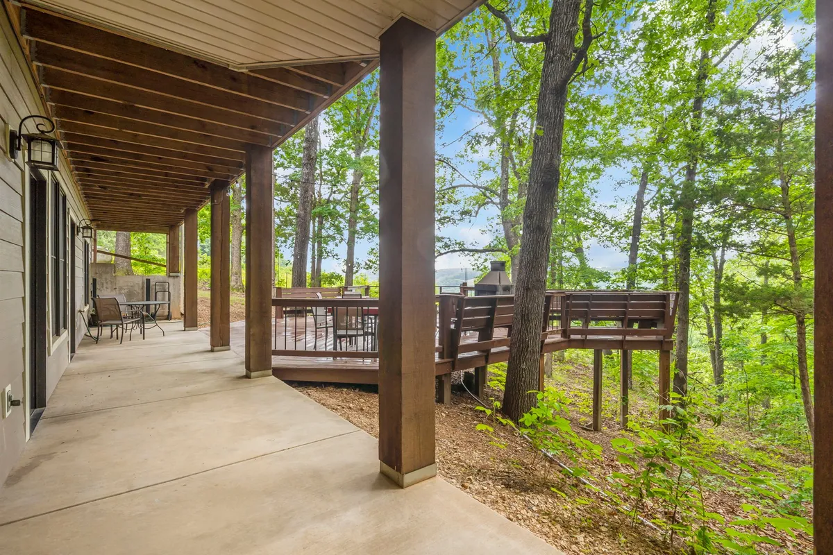 A spacious wooden deck set amid tall trees, with comfortable outdoor seating for relaxing or gathering. The deck seamlessly blends into the natural landscape, emphasizing a strong connection to the outdoors.